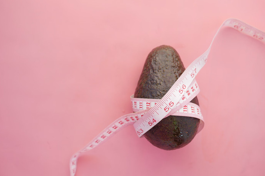 A measuring tape wrapped around an avocado, representing the holistic approach to weight management