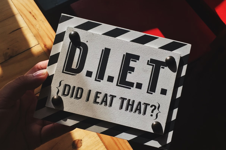 A person holding a quote board with the word "DIET" written on it, representing the significance of nutrition in weight management